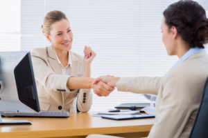 Smartly dressed young women shaking hands in a business meeting at office desk