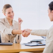 Smartly dressed yyoung women shaking hands in a business meeting at office desk