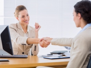 Smartly dressed yyoung women shaking hands in a business meeting at office desk